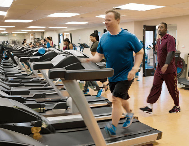 A man with mild autism walks steadily on a treadmill, focused, with gentle movements, surrounded by gym equipment and the hum of exercise machines.